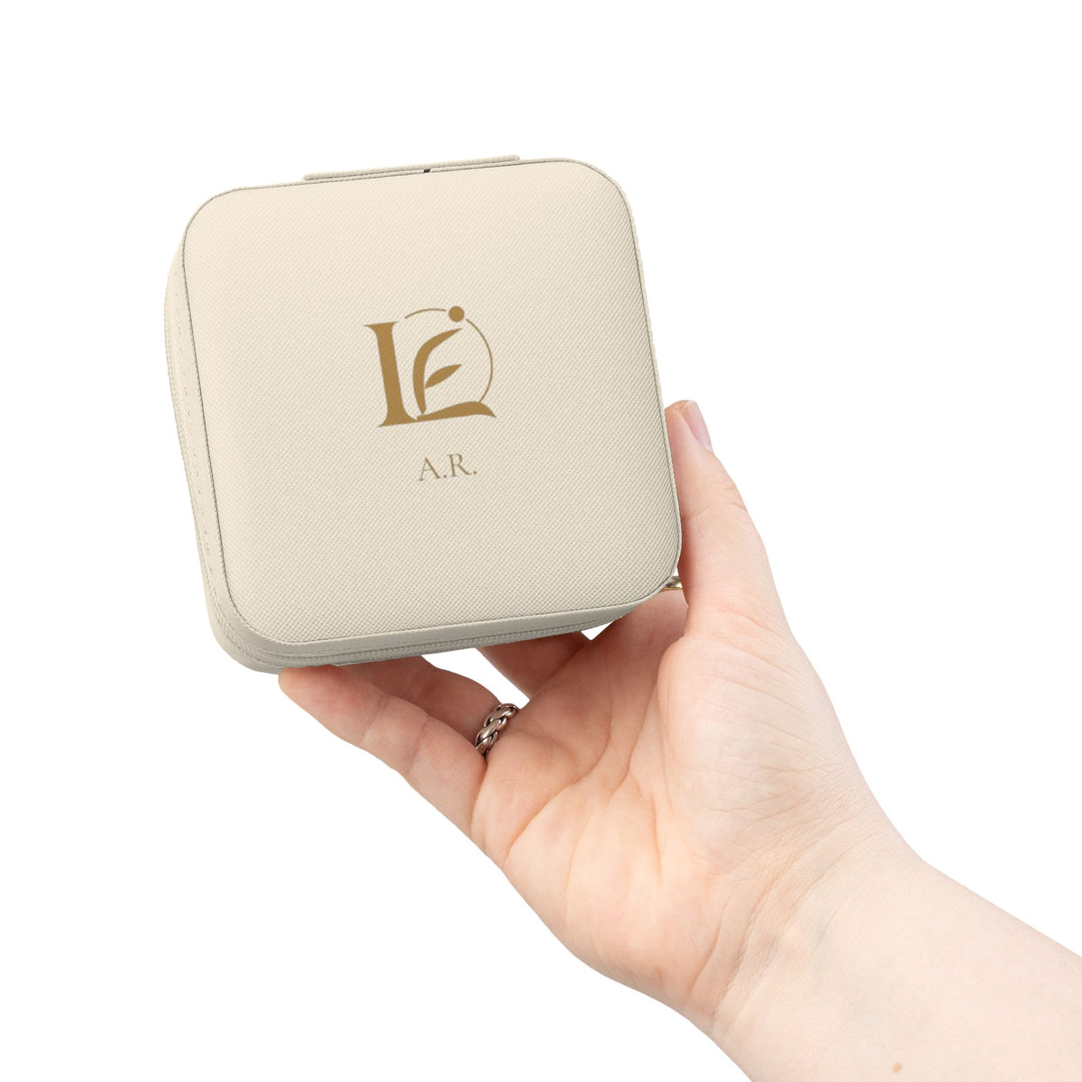 The Keepsake Travel Case in ivory, held in hand, with gold Lyfe Element mark and initials